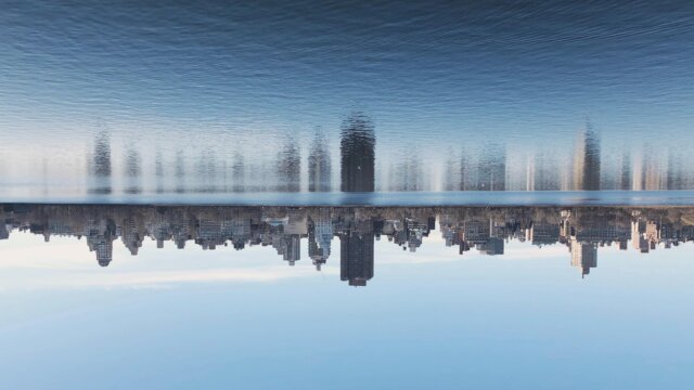 Visuelle Kommunikation am Beispiel einer Stadt, die sich in See-Wasser spiegelt. Das Spiegelbild füllt die obere Hälfte des Bildes, die reelle Aufnahme, die untere Hälfte.